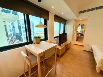 a living room with a table and a large window at Warm Minimalist Studio , Walk to Metro , Pool, Gym in Dubai