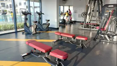 a gym with tread machines and people in the background at Warm Minimalist Studio , Walk to Metro , Pool, Gym in Dubai