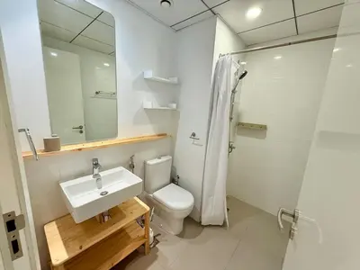 a bathroom with a sink and a toilet and a mirror at Warm Minimalist Studio , Walk to Metro , Pool, Gym in Dubai