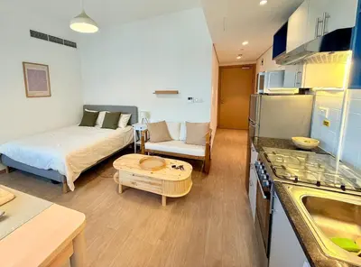 a kitchen and a living room with a bed and a table at Warm Minimalist Studio , Walk to Metro , Pool, Gym in Dubai