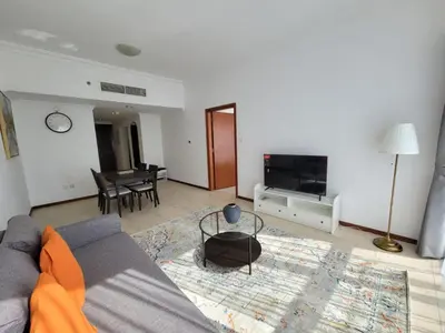 a living room with a couch and a tv at One Bedroom Apartment in Mag 214, JLT in Dubai