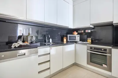 a kitchen with white cabinets and silver appliances at Frank Porter - Dubai Marina Mall Hotel in Dubai