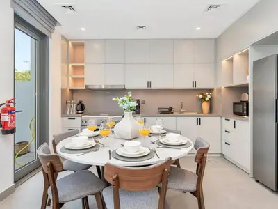 a kitchen with a table with chairs and a vase with flowers at Royal Vista 26 - 4BR Villa at Arabian Ranches III in Nadd Shubayḩ