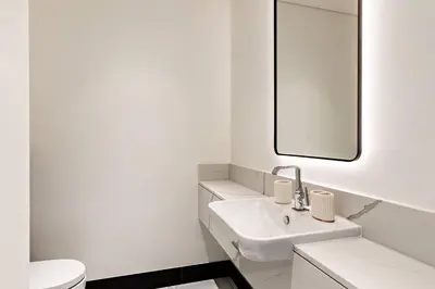 a white bathroom with a sink and a mirror at Luxury 1BR Duplex on the Canal Business Bay in Dubai