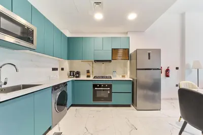 a kitchen with blue cabinets and a stainless steel refrigerator at Elegant 2BR Retreat at Opalz Arjan in Dubai