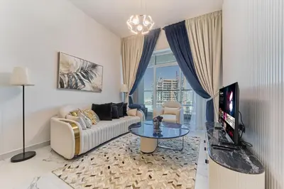 a living room with a couch and a table and a tv at Elegant 2BR Retreat at Opalz Arjan in Dubai