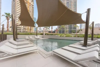 a swimming pool with lounge chairs and an umbrella at Stayshort - 1 Bedroom in Business Bay with Canal Views that Sleeps 4 in Dubai