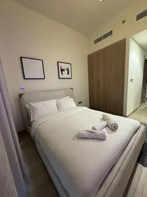 a bedroom with a large white bed with towels on it at Iconic Studio in Azizi 48 with Pool and Gym in Dubai