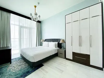 a bedroom with a white bed and a large cabinet at Blissful Escape 2 BDR In Bayz-19 in Dubai