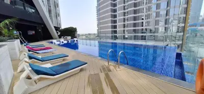 a swimming pool with lounge chairs next to a building at Blissful Escape 2 BDR In Bayz-19 in Dubai