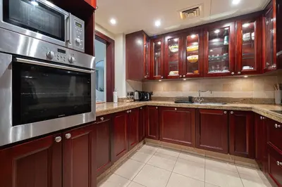a kitchen with wooden cabinets and stainless steel appliances at Dubai Icon Suite at Miska 2 in Dubai