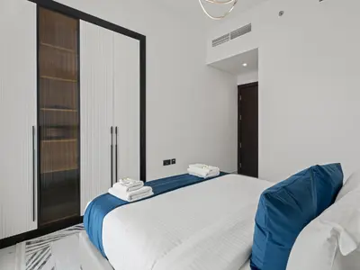 a bedroom with a large white bed with blue accents at Opalz Grandeur Escape 2BDR w Mini Pool-06 in Dubai