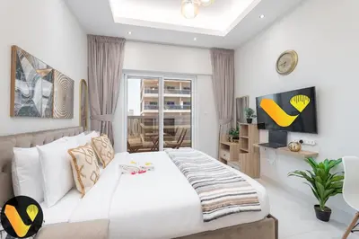 a bedroom with a large white bed and a tv at Vogue Sports City Hera Tower Near First Avenue Mall, Studio Apartment with Balcony, Canal and City View, Access to all Amenities in Dubai