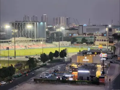 a view of a city at night with a parking lot at Vogue Sports City Hera Tower Near First Avenue Mall, Studio Apartment with Balcony, Canal and City View, Access to all Amenities in Dubai