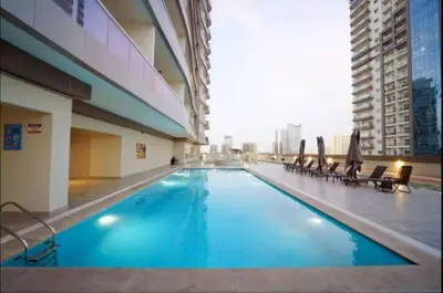 a large swimming pool in a building with chairs at Vogue Sports City Hera Tower Near First Avenue Mall, Studio Apartment with Balcony, Canal and City View, Access to all Amenities in Dubai