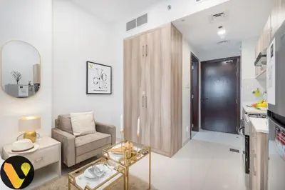 a white living room with a chair and a table at Vogue Sports City Hera Tower Near First Avenue Mall, Studio Apartment with Balcony, Canal and City View, Access to all Amenities in Dubai