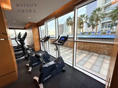 a gym with cardio equipment in a building with a large window at Modern Luxury Studio Damac Hills With Golf View in Dubai