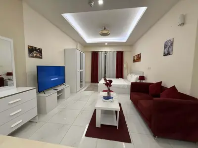 a living room with a red couch and a tv at Chic Studio in Dar Al Jawhara Residence in Dubai