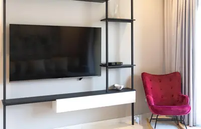a living room with a tv and a red chair at Stunning 3BDR in Al Sidir Greens in Dubai