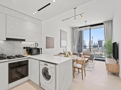 a kitchen with a washer and dryer and a living room at Aesthetic Elegance 1BDR in Binghatti Onyx in Dubai