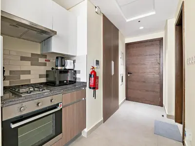 a kitchen with a stove top oven next to a door at Modern Studio In Al-Furjan close to Metro-15 in Dubai