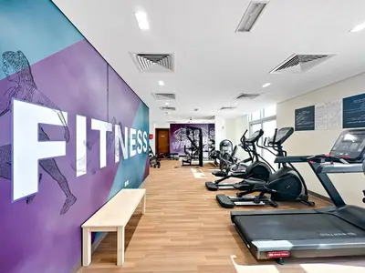 a gym with treadmills and cardio equipment in a room at Modern Studio In Al-Furjan close to Metro-15 in Dubai