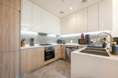 a kitchen with white cabinets and a sink at 2 Bedroom in Peninsula with Burj View in Dubai
