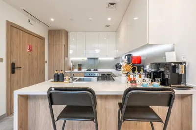 a kitchen with two chairs sitting at a counter at 2 Bedroom in Peninsula with Burj View in Dubai