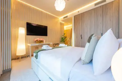 a bedroom with a large white bed and a tv at 2 Bedroom in Peninsula with Burj View in Dubai