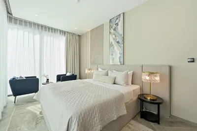 a bedroom with a white bed and a blue chair at 2BD Stylish Apartment with Amazing Canal Views in Dubai