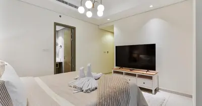 a white bedroom with a large bed and a flat screen tv at Burj View 2BHK Downtown Infinity Pool in Dubai