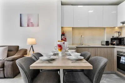 a living room with a table and chairs and a kitchen at Beautiful 2BR at Majestique Residence Dubai South in Dubai