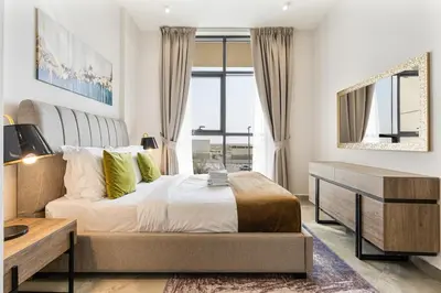 a bedroom with a bed and a desk and a window at Beautiful 2BR at Majestique Residence Dubai South in Dubai