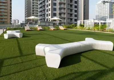 a white bench on a field of grass with buildings at Stylish 1BR at Binghatti Phantom with Private Pool in Dubai