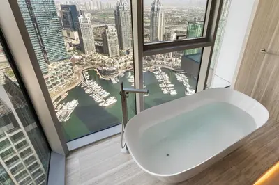 a bathroom with a white bath tub in front of a window at LIV Marina, Dubai Marina - 4 Bedroom Penthouse with Panoramic Views - Allsopp & Allsopp in Dubai