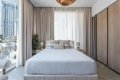 a bedroom with a white bed and a large window at GuestReady - Premium Location | Studio | Pool View in Dubai