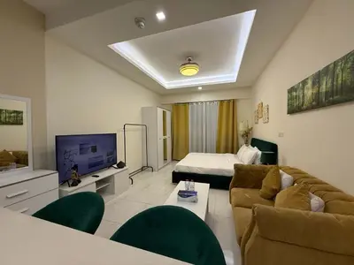a living room with a couch and a television at Refined Studio at Dar Al Jawhara in Dubai