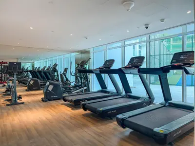 a gym with rows of treadmills and elliptical machines at Chic Studio near Dubai Miracle Garden & Expo City in Dubai