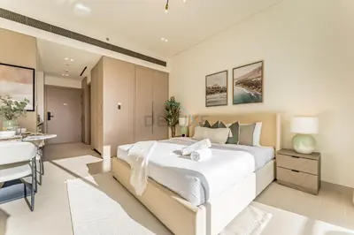 a bedroom with a large white bed and a table at Well-Appointed Studio, Minutes from Circle Mall and Community Parks - Binghatti Phoenix, Jumeirah Village Circle by Deluxe Holiday Homes in Dubai