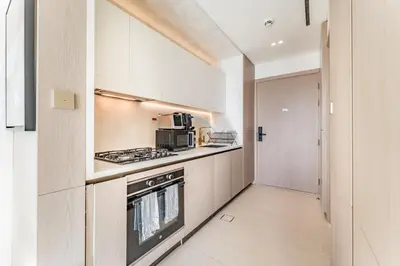 a kitchen with white cabinets and a stove top oven at Well-Appointed Studio, Minutes from Circle Mall and Community Parks - Binghatti Phoenix, Jumeirah Village Circle by Deluxe Holiday Homes in Dubai