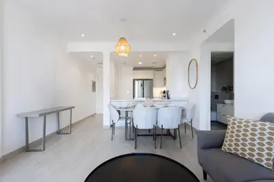 a kitchen and living room with a table and chairs at Contemporary 2BR in JVC With Pool, Gym & Relaxing Stay in Dubai