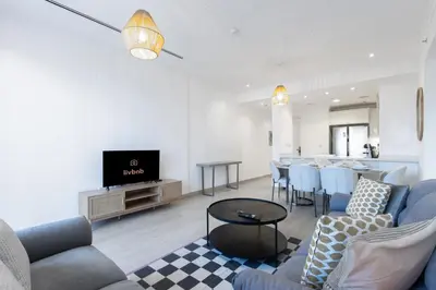 a living room with a couch and a table at Contemporary 2BR in JVC With Pool, Gym & Relaxing Stay in Dubai
