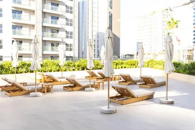 a group of lounge chairs and umbrellas on the roof of a building at Spacious and Cozy Apartment - Binghatti Phantom 2404 in Dubai