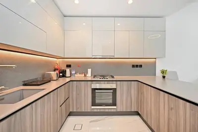 a kitchen with white cabinets and a counter top at Luxury 1BR at Royal Regency, Refined City Living in Dubai