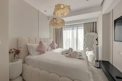 a white bedroom with a large bed and a chandelier at Waves - JW Marriot Residence Modern & Chic 1BR Apt in Dubai