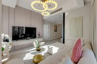 a living room with a white couch and a television at Waves - JW Marriot Residence Modern & Chic 1BR Apt in Dubai