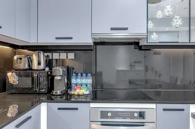 a kitchen with white cabinets and bottles of water at Waves - JW Marriot Residence Modern & Chic 1BR Apt in Dubai
