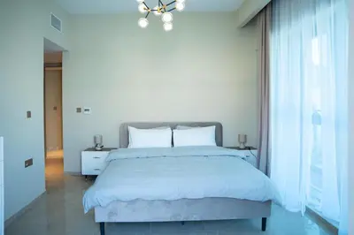 a white bedroom with a large bed and a chandelier at Italian-Design 2BR l Large Private Terrace l Ground Floor in Dubai