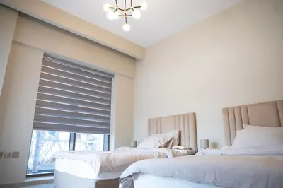 a bedroom with two beds and a window with a chandelier at Italian-Design 2BR l Large Private Terrace l Ground Floor in Dubai