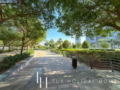 a walkway in a park with trees and buildings at LUX The Armada Suite JLT in Dubai